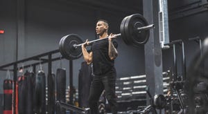 man working out in a gym with barbell and weights