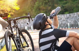 mature man drinking water from the bike bottle while riding a bike