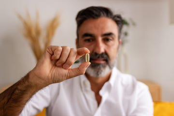 mature man holding pill in focus