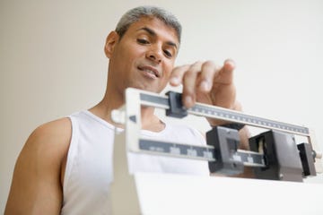 middle aged man weighing himself