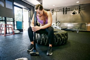 Mixed Race woman resting on tire holding sledgehammer in gymnasium