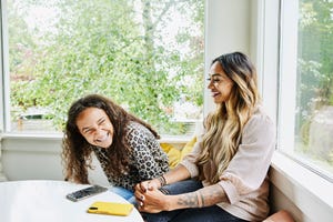 medium shot of mother and daughter laughing together while hanging out in living room