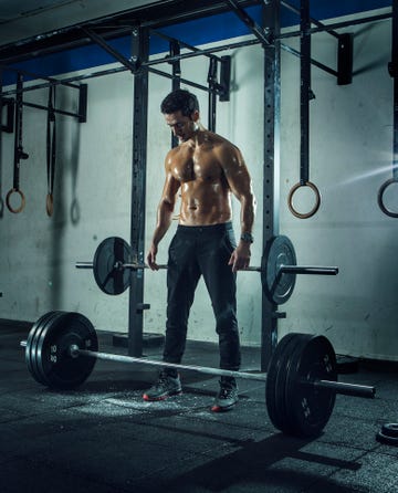 muscular built man preparing to lift barbell