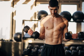 muscular shirtless man exercising with dumbbells