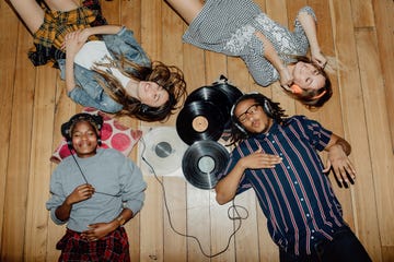 group of young friends listening to music with vinyls scattered about