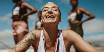 an athlete with a medal around her neck smiling as other athletes stand in the background