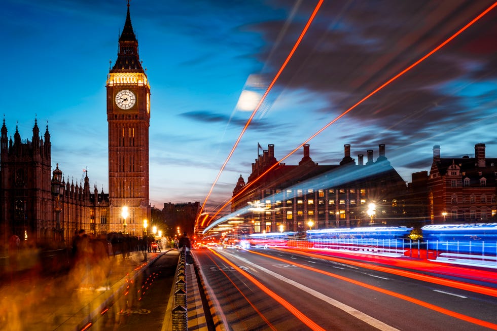 london at dusk, big ben seen from westminster bridge with lights trails created by traffic on the right i blurry motion people on the left