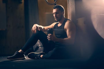 a man sitting on the floor holding a glass of beer