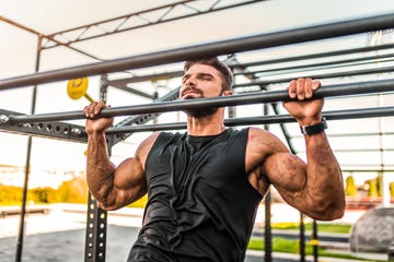 young male athlete exercising at the gym he is doing pull ups at the health club