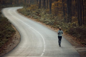 rear view of a female athlete jogging on the road in nature