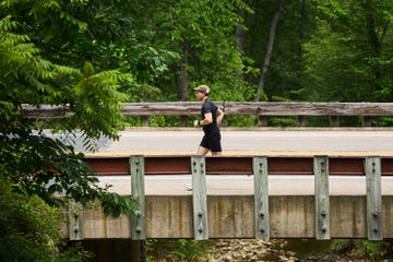 a runner passes over a bridge with a creek below it