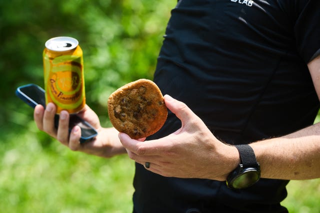 a man holding a cookie and a seltzer