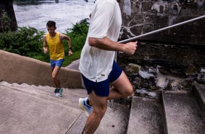 two runners go up a set of stairs with a river in the background