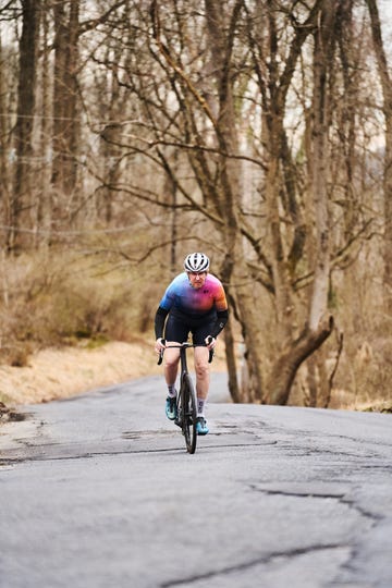 a person riding a bicycle on a road with trees on the side