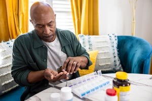 senior man sorting prescription medications at kitchen table