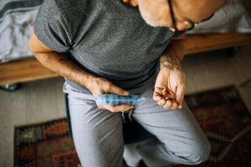 senior man taking medications from a daily pill organizer