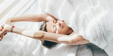 woman sleeping under duvet on a sunny morning, top view