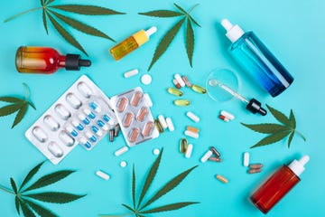 set of products made of cannabis on turquoise background with cannabis leaves multicolored glass bottles with cbd oil, pills, blister packs and glass pipette with oil from cannabis in petri dish top view