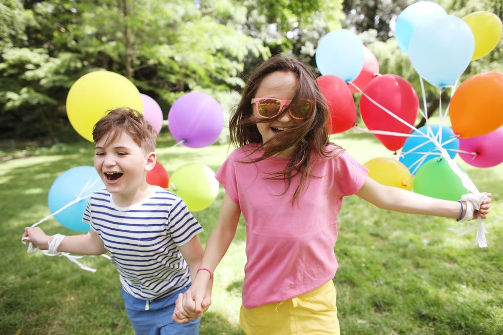 brother and sister running together with balloons