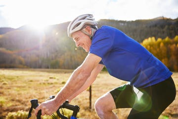 longevity tests side view of smiling senior man riding bicycle during sunny day