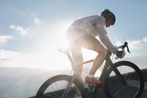 silhouette of cyclist riding up in high mountains at sunrise