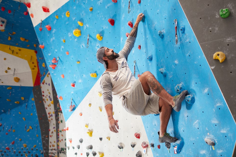 Sporty mature man climbing wall in gym