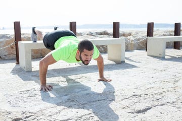 strong man doing feet elevated push ups at seaside