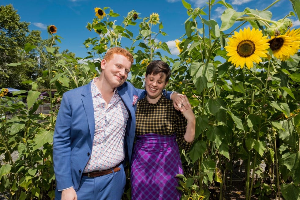 natalie beach and her husband stand among sunflower stalks on their wedding day