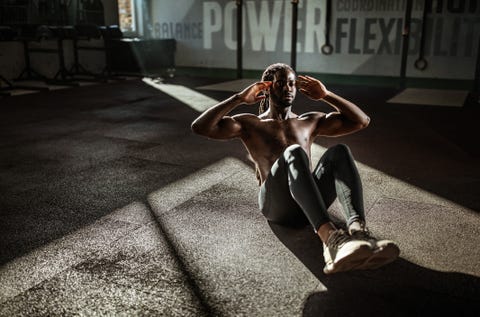 sweaty black athlete doing sit ups in a gym