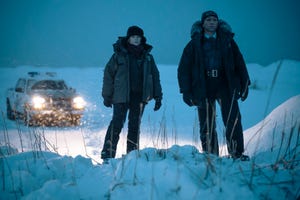 two detectives stand in the middle of the snow looking out into the distance