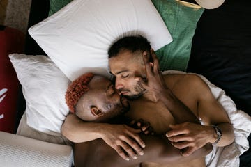 two gay men fondly embracing in bed