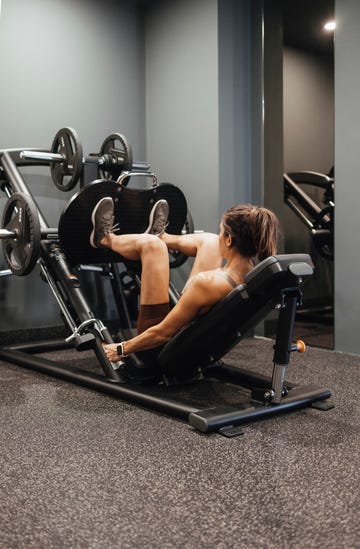 unrecognizable woman working out on a leg press machine at the gym