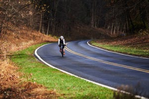 a person riding a bike on a road surrounded by trees