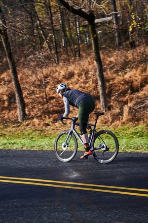 a person riding a bicycle on a road with trees on the side