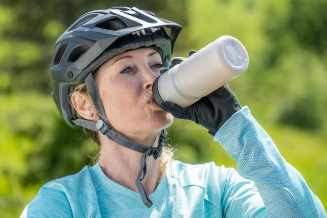 woman in helmet drinking water