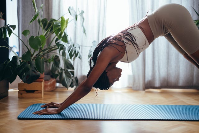 stretching before bed woman standing in downward facing dog pose at home