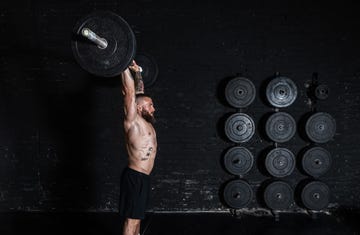 young active strong fit muscular sweaty man with big muscles doing barbell weight lifting cross training workout in the gym dark image real people