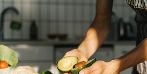 young man cooking guacamole in light kitchen at home hands close up