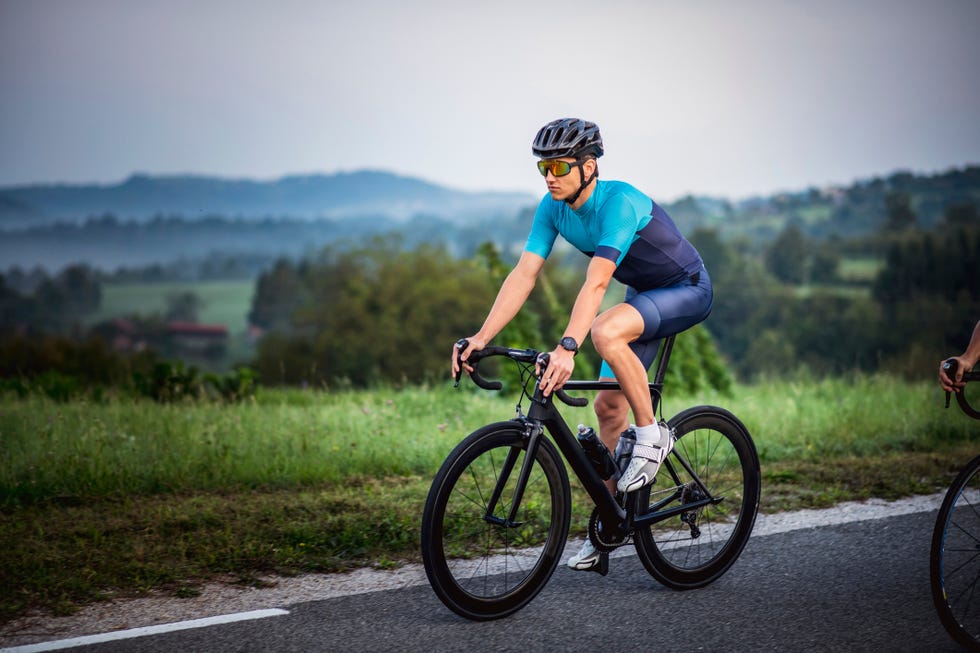 young man cycling through summertime rural landscape