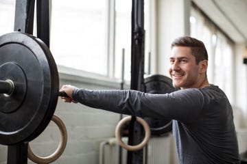 young man exercising with barbell at gym