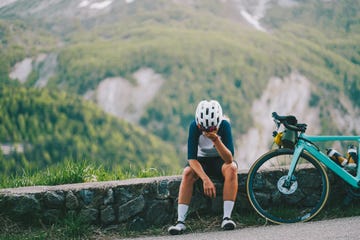 young woman bicyclist pause on road in mountains