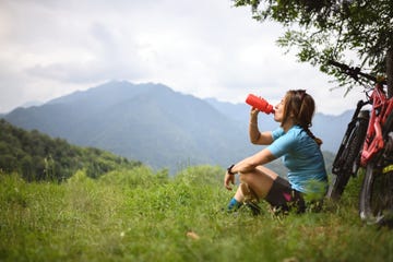 young woman with mountain bike on italian mountains drinking water