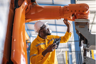 Homem trabalhador industrial atuando sobre um braço robótico