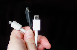 Alt: Mãos segurando três cabos usb