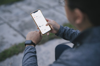 Homem olha celular enquanto usa um smartwatch na rua.