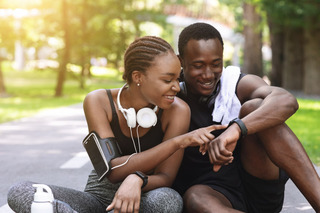 Casal checa os dados de um smartwatch após exercício físico.