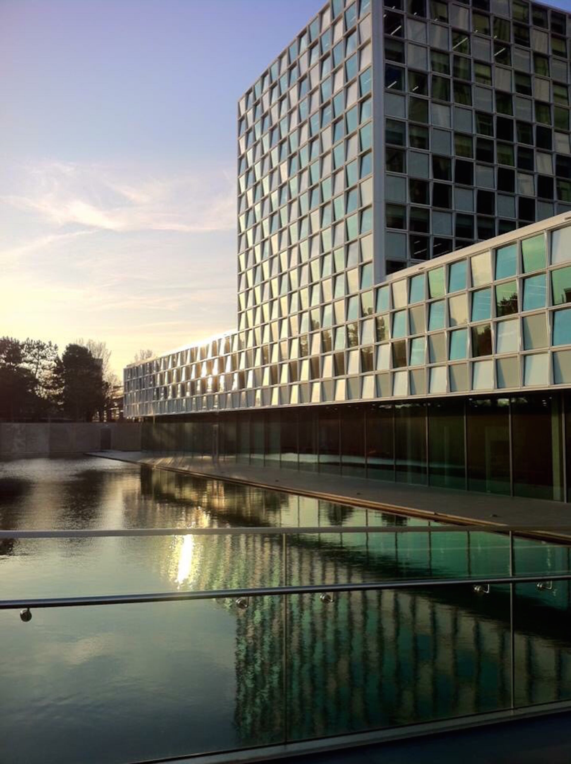 A building next to a fountain at sunset or sunrise.