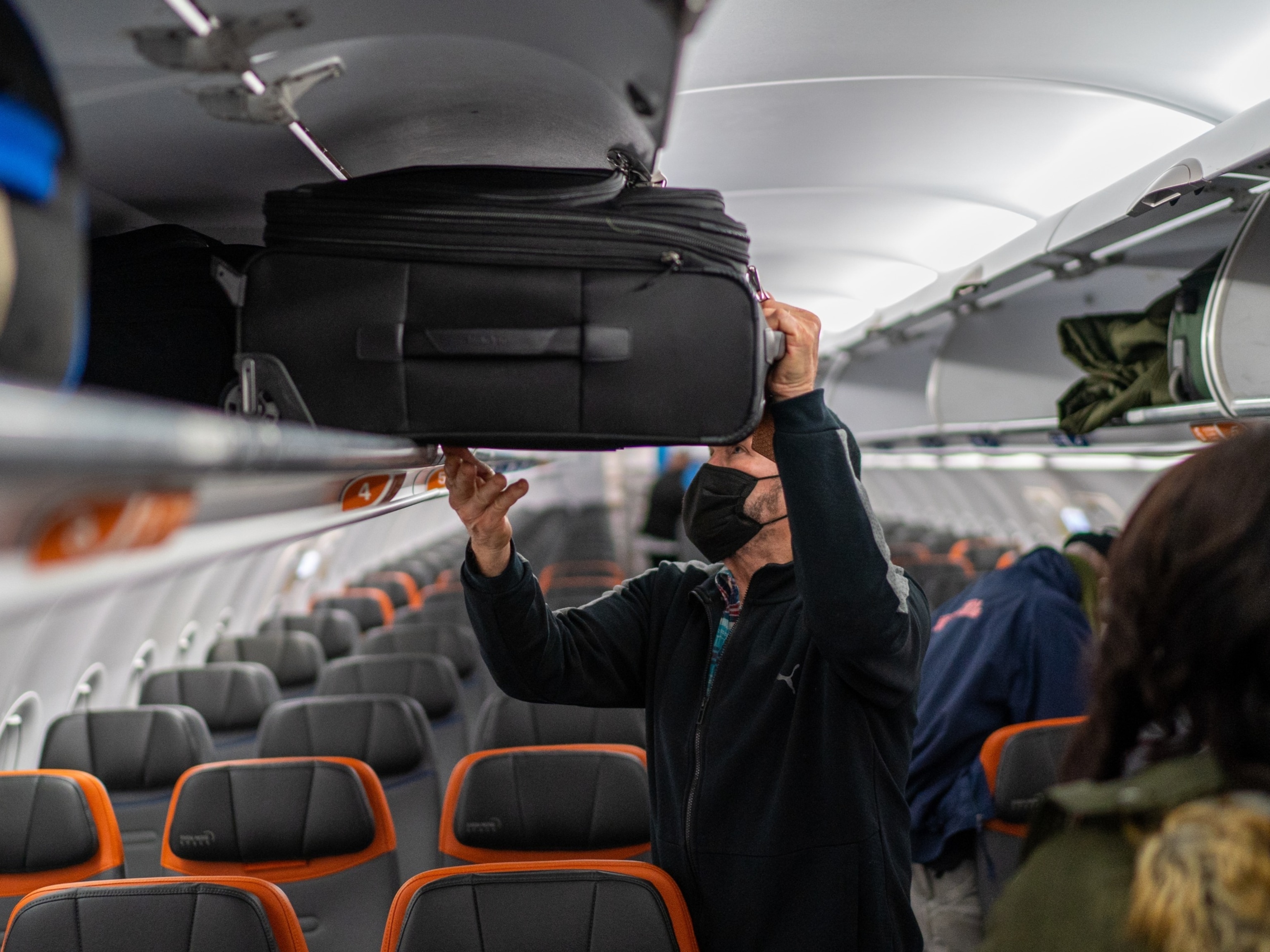 PHOTO: A JetBlue passenger puts his carry-on luggage into an overhead compartment January 28, 2022 at John F. Kennedy International Airport in New York City.