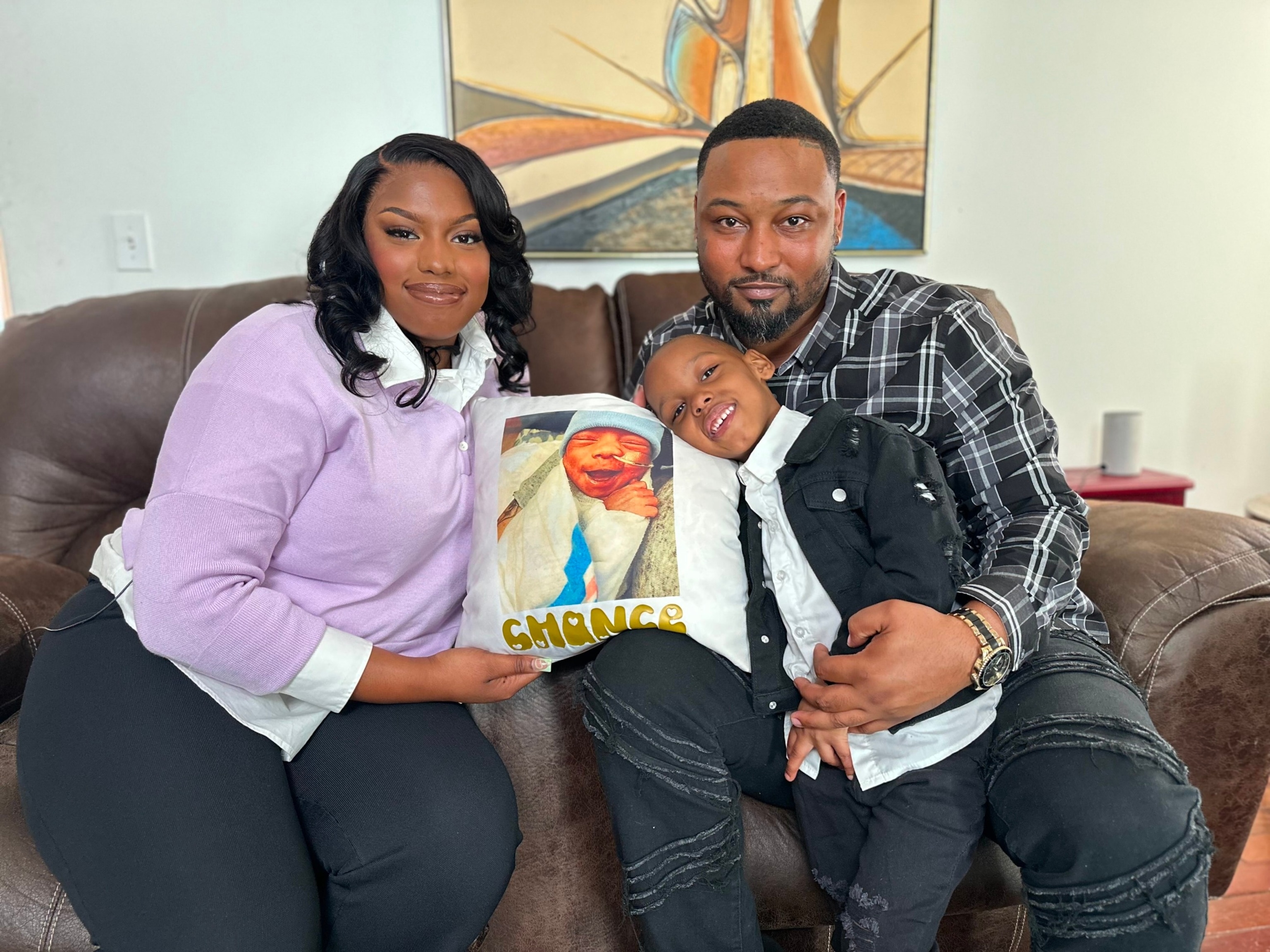 PHOTO: Jasmine Watson sits with her partner, Cedric Dean, and their son Chase, 4.  Pictured on the pillow is Chance Dean, who died from NEC in March, 2020.