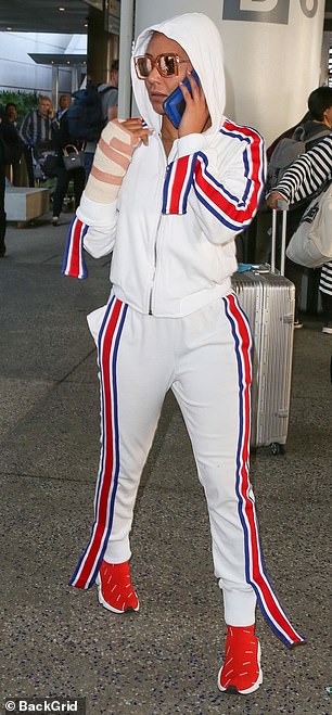 Casually clad: Mel seemed engrossed in a phone call as she caught the eye in a bright white tracksuit while making her way through LAX airport on Friday